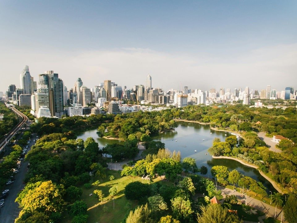 Modern Bangkok skyline behind park and lake, seen on city sightseeing tours